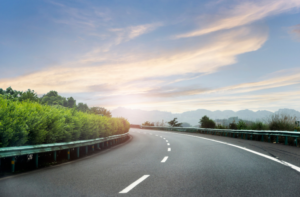 Image of a road with mountains and trees surrounding.