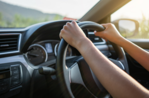 Hands on car steering wheel.