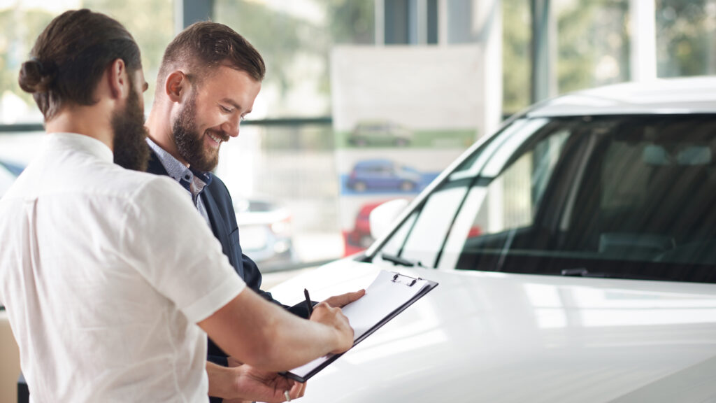 A car dealer looking over paperwork with their customer at a dealership.